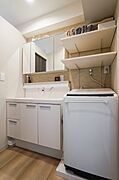 三面鏡付きの洗面化粧台と、上部に可動棚が備わった洗濯機置き場。壁面のアクセントクロスはトイレとお揃いです。