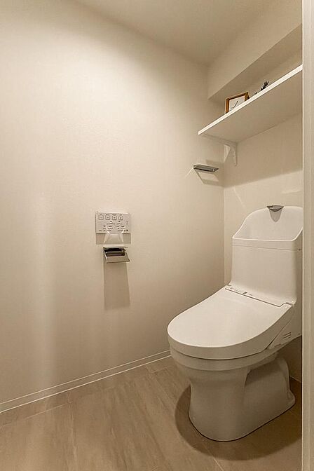 トイレは洗面室からアクセスする間取り。シンプルなデザインで、上部にはオープン収納が備わっています。