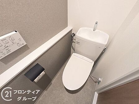 【トイレ】リフォーム済みで気持ちよく使えるトイレ。温水洗浄便座と手洗い付きタンクを備えています。グレーのアクセントクロスが空間を引き締め、ペーパーホルダー上の棚にはちょっとした小物も置けて便利です。
