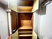 玄関に設けられた木目調の収納棚です。上下段には複数の棚板が配置され、靴類を整理して保管するスペースが確保されています。中央部のオープンスペースは、小物を置くカウンターとして活用可能な造りです。