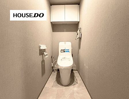 温水洗浄便座付きの清潔感あるトイレ。上部には収納棚があり、トイレットペーパーなどを整理できます。