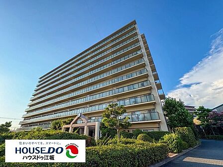 青空に映える堂々とした佇まいが印象的なマンション外観。周囲には豊かな植栽が整えられており、緑の潤いを感じられるアプローチが魅力的です。落ち着いた街並みに調和する、格式高く安心感のある佇まいです。