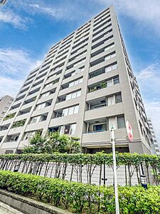 外観：落ち着いたグレーのタイル貼りが洗練された印象を与える高層マンション。敷地沿いには整えられた緑豊かな植栽が配され、都市の利便性と心地よい住環境を両立。凛とした存在感を放つ佇まいです。
