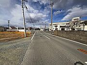 砂利道の前の道路です。右手の白い建物はいわき市役所勿来支所。