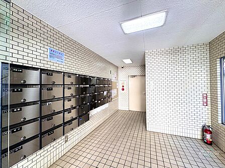 ステンレス調の集合ポストが整然と並ぶエントランス。各住戸の表札も確認でき、管理の行き届いた清潔感あふれる安心の共用スペースとなっています。