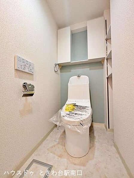 新規交換済みの温水洗浄便座付きトイレ。上部の吊戸棚やサイドの可動棚など、限られた空間を有効活用した便利な収納が充実しています。