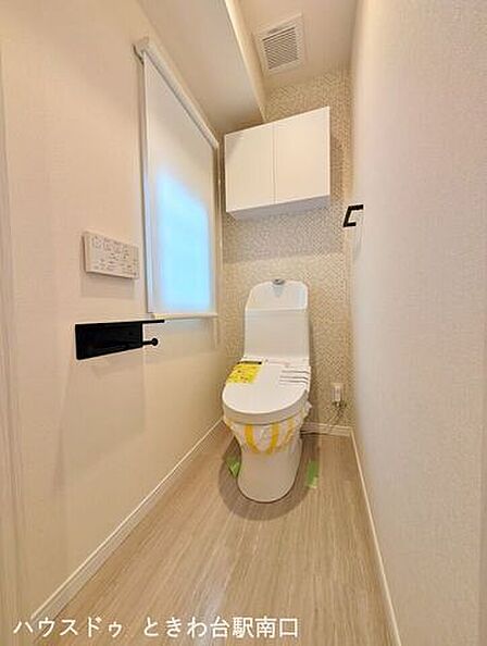 温水洗浄便座付きのトイレです。落ち着いた雰囲気のアクセントクロスを配し、上部には扉付きの吊戸棚を設置しているため、備品をすっきりと収納できます。