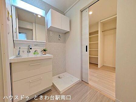 三面鏡タイプの洗面化粧台です。鏡裏に小物を収納でき、横には洗濯機置き場と吊戸棚を配置。効率的な家事動線に配慮した、使い勝手の良いサニタリー空間です。