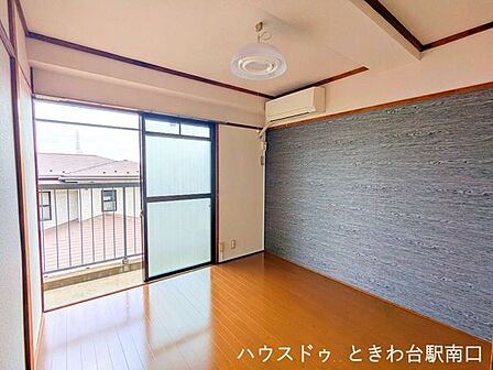 洋室はバルコニーに面し、明るい光が差し込みます。落ち着いた木目調のアクセントクロスが印象的な空間です。