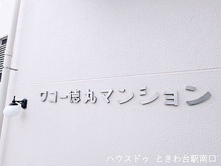 ホワイトの外壁に映えるマンション銘板。落ち着いた住環境を象徴するシンプルで洗練されたデザインが、住まう方を優しく出迎えます。