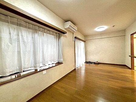 リビング　豊かな自然光が心地よく広がり、木目の美しい床面が穏やかな空間を演出する落ち着いた雰囲気の室内です。 