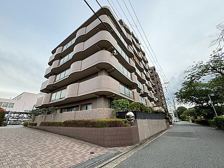 流れるような曲線を描くバルコニーが印象的な外観は、落ち着いた色合いのタイルと調和し、街並みに上品な存在感を放つ佇まいとなっています。