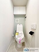 白を基調とした清潔感のあるトイレ。上部に収納もついておりますので、とても便利です。