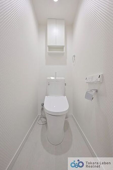 白を基調とした清潔感のあるトイレ。上部に収納もついておりますので、とても便利です。