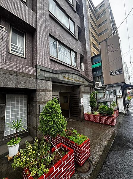 ブラウンのタイル張りが印象的な外観。エントランスには植栽が配され、落ち着いた雰囲気を演出しています。