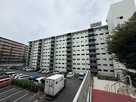 落ち着いた色調の外観が街並みに調和するマンションです。ゆとりのある駐車場が日々の暮らしをサポートします。
