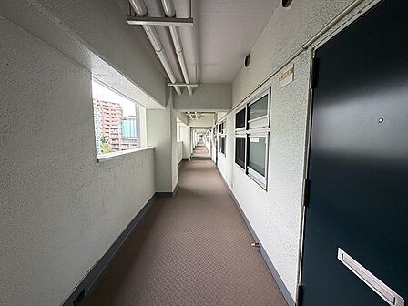 長い廊下が続く、集合住宅の共用廊下です。外廊下のため採光があり、開放感があります。