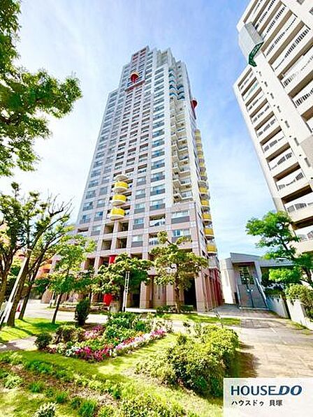重厚感のあるエントランスが印象的なマンションです。青空に映える明るい外観で、管理の行き届いた清潔感のある佇まい。