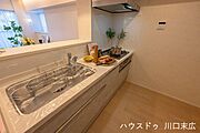 調理中も家族と視線が合う対面式キッチン。木目調のパネルが空間に温かみを添えます。広いワークトップは作業効率が良く、毎日の家事を楽しくサポートする設計です。