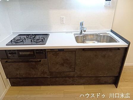 落ち着いた色合いのパネルが空間に美しく馴染むシステムキッチン。作業スペースをしっかりと確保しており、毎日の調理や片付けをスムーズにサポートします。