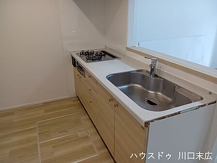 木目調の面材が美しい機能的なシステムキッチン。使い勝手の良いワークスペースを備え、毎日の調理や後片付けをスムーズに行える洗練された設備です。