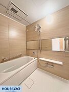木目調のパネルが落ち着いた印象を与える浴室です。雨の日の衣類乾燥に便利な浴室乾燥機や、横長で空間を広く見せるミラーを設置。手すりも備わっており、どなたでも安心して入浴を楽しめる配慮がなされています。