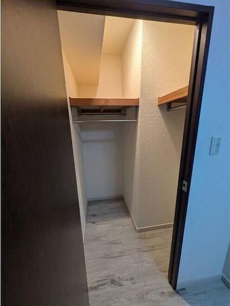 お部屋のフローリングと統一感のある床面で仕上げられた、L字型のウォークインクローゼットです。デッドスペースを減らし、限られた広さを有効に活用できるように設計されています。