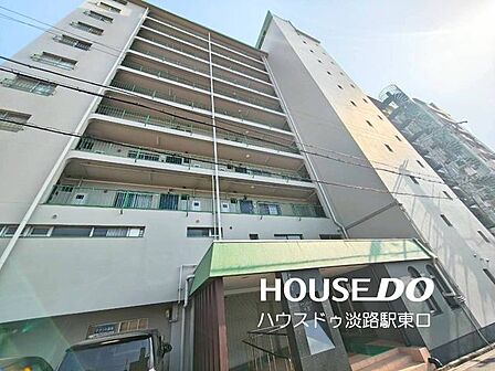 直線的な意匠と落ち着いたグレー基調の外観が印象的なマンション。アプローチ部分には緑色の庇が設けられており、雨の日の出入りにも配慮された構造です