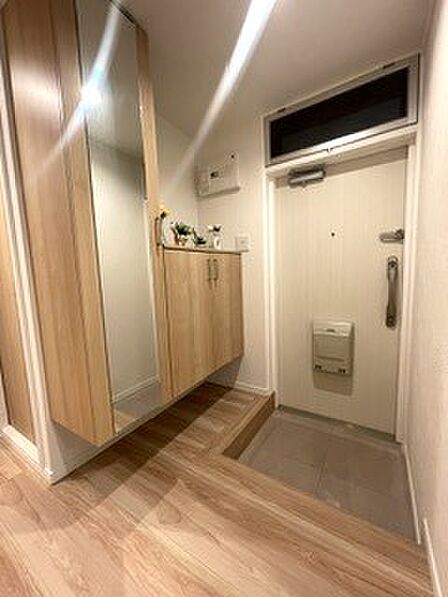 温かみのある木目調のデザインでまとめられた明るい玄関。お出かけ前の身だしなみチェックに重宝する、大きな鏡付きのシューズボックスを備えているのが嬉しいポイントです。