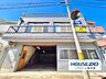 外観：前面道路から建物全体が見渡せる外観。明るい空と白い外壁がよく映えています。