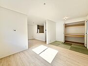 【光あふれる、家族のメインステージ】大きな窓から差し込む陽光が心地よいリビング。木目調のフロアが温かみを演出し、キッチンや畳エリアとも自然に繋がり開放的で、それぞれの時間を共有できる場所。