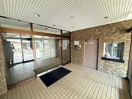 レンガ調の壁とタイル床が落ち着いた雰囲気をつくるエントランス。ガラス扉から光が入り、外とのつながりを感じられます。管理事務所窓口も設けられています。室内と合わせて、共用部分の使い勝手もご確認ください。
