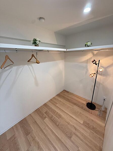 棚とハンガーパイプを備えたウォークインクローゼット。衣類を掛けたり、棚に箱やバッグを置いたりと使い分けられます。収納ケースを組み合わせて小物も整理でき、居室をすっきり使うために役立つ収納スペースです。