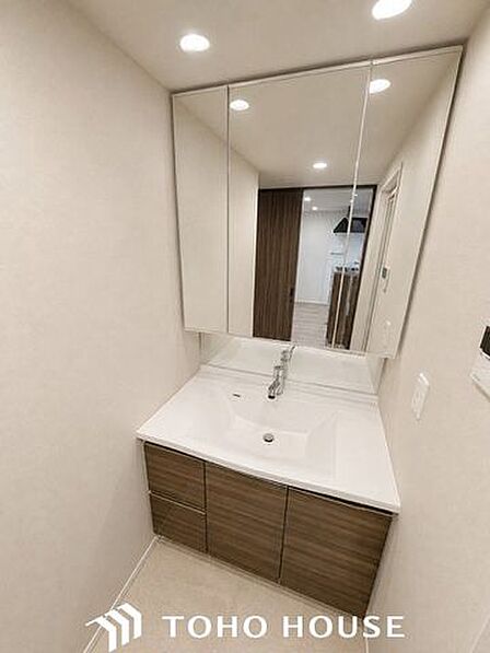大きく見やすい三面鏡で清潔感ある洗面台。収納も多く、コスメ等もスッキリと仕舞えます。※現況写真にAIによる画像処理(家具等を消す)がされています。