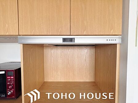 炊飯器や電気ポットなどの家電を置き、調理時に発生する蒸気を上部のファンで外部へ排出することで、棚板の結露や劣化を防ぐための収納スペースです。※現況写真にAIによる画像処理(家具等を消す)がされています