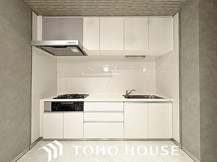 グレーの腰壁や木目調の天井など、こだわりの内装と美しく調和するスタイリッシュなキッチン。リビング側からの見た目もお洒落で、住まい全体のインテリア性を高める意匠性の高い空間です。
