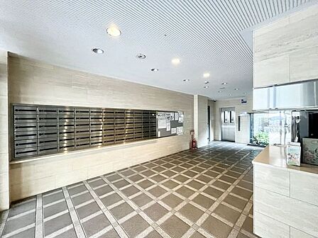 タイル張りのエントランスホールです。集合ポストが並ぶ明るい共用空間です。