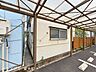 外観：屋根付きスペースから建物の側面まで確認できる一枚。敷地内の動線や設備もご覧いただけます。