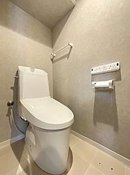 【トイレ】温水洗浄便座と壁掛けリモコンを備えた清潔感あふれるトイレ空間。