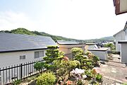 手前の緑豊かなお庭と、奥に広がる山並みが調和した景色 。落ち着いた住環境を実感できる眺望です 。