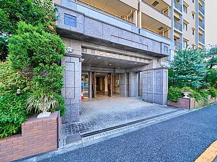 天然石仕上げのエントランスとダークブラウンの木製ドア