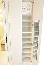 玄関入って正面にある可動棚の収納です。扉の内側に鏡があり、お出かけ前の身だしなみチェックに役立ちます。下駄箱は玄関タタキにあります。