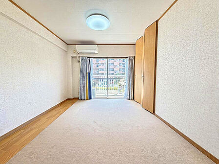 バルコニーから明るい陽光が注ぐ広々リビング。便利な壁面物入ですっきり整う空間。