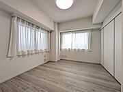 2面に窓を設けた、明るく風通しの良い快適な洋室。壁一面に広々としたクローゼットが配置されており、荷物や衣類をすっきりと収納できます。白を基調とした内装と木目調の床が落ち着く住空間です。