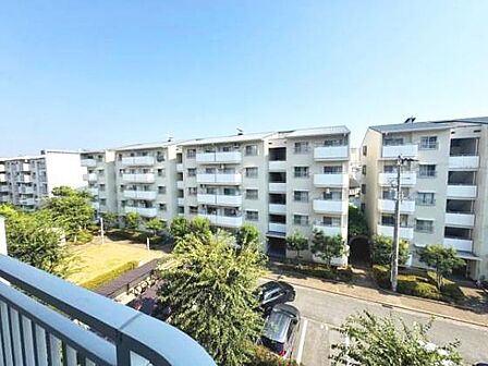 バルコニーからの見晴らしが開放的です。周囲には同様の建物が並び一体感のある雰囲気です。緑が多く住環境のバランスが感じられます。道路や駐車場が整備され安心感があります。