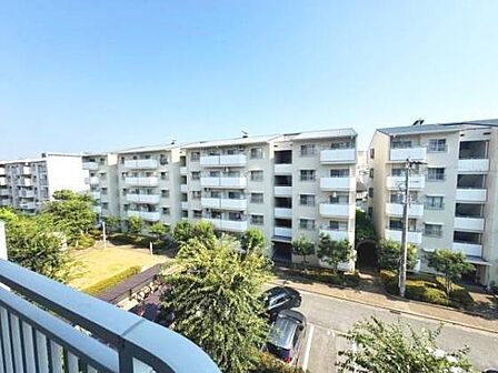 バルコニーからの見晴らしが開放的です。周囲には同様の建物が並び一体感のある雰囲気です。緑が多く住環境のバランスが感じられます。道路や駐車場が整備され安心感があります。