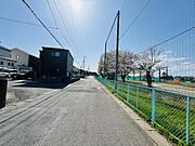 前面道路は幅員が十分にあり車の通行もスムーズです。周囲には住宅や公園開放感のあるフェンスが続いています。陽当たりが良好で舗装も整っています。見通しも確保された現地環境となっています。