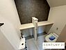 トイレ：手洗い器やカウンターを備えた機能的なトイレ空間です。アクセントクロスを取り入れたシックなデザインで、清潔感と落ち着きのある落ち着いた雰囲気に仕上げています。