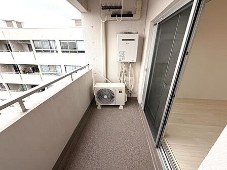 開放感のあるバルコニーです。室外機や給湯器がコンパクトに配置されており空間がしっかり確保されています。隣室との仕切りがシンプルで圧迫感がありません。床面は落ち着いた色合いで整えられています。