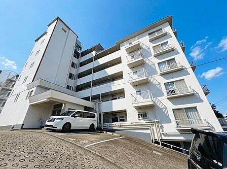 白を基調とした外観が印象的な建物です。青空とのコントラストが際立ち明るい印象を与えます。バルコニー付きの住戸が多く爽やかな雰囲気が特徴的です。敷地内には駐車スペースも確保されています。
